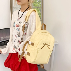 Détail du sac à dos en toile jaune clair avec broderie nœud marron et sangles à boucles