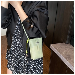 Détail du sac seau vert menthe montrant le cuir texturé et la boucle en U argentée