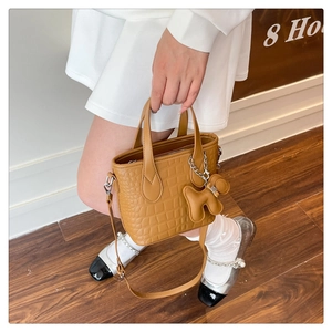 Detailed view of crocodile embossed leather bucket bag with a cute puppy-shaped charm