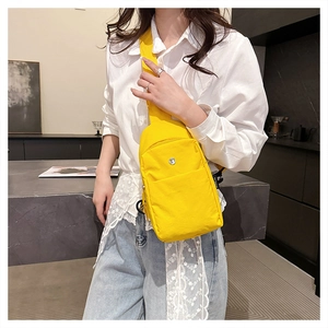 Detailed view of lightweight yellow nylon crossbody chest bag with round metal buckle
