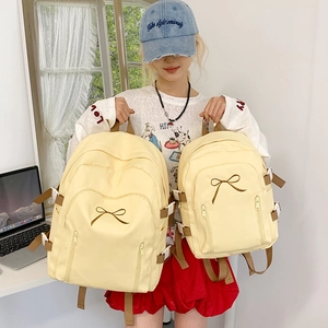 Comparaison de grands et petits sacs à dos en toile jaune avec broderie nœud mignon