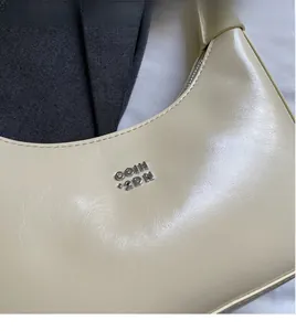 Detailed macro view of the cream-colored synthetic leather texture and silver logo