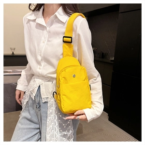 Detail view of bright yellow nylon chest bag with adjustable black strap on a model
