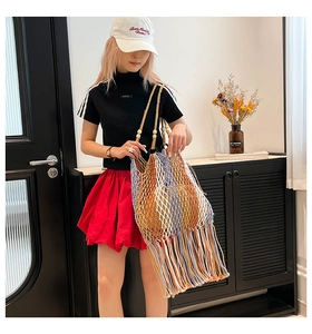 Detail of bohemian hand-woven tote bag with colorful tassels and wooden bead handle