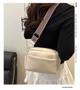 Close-up of cream lychee texture crossbody bag with wide striped fabric shoulder strap