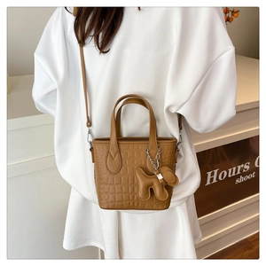 Brown crocodile-pattern bucket bag with a cute dog pendant and adjustable shoulder strap