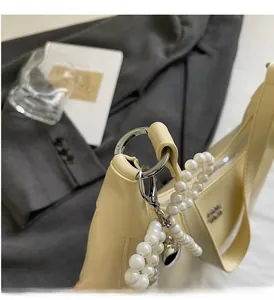 Detail of elegant handbag featuring large silver rings and a decorative pearl chain strap