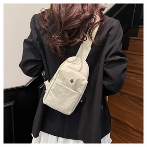 Detail of a beige pleated nylon crossbody bag showing fine texture and metal logo