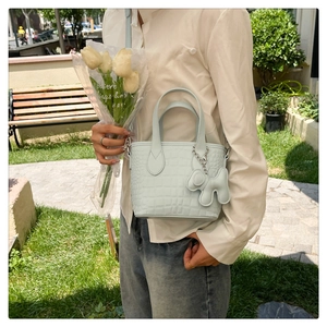 Detail of light blue faux crocodile texture bucket bag with cute cloud charm