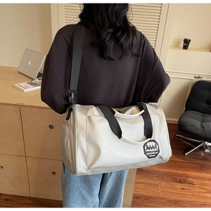 Sac de voyage argenté imperméable avec bandoulière porté par un mannequin