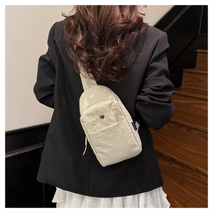 Detail of a beige nylon chest bag with adjustable strap shown from a back perspective