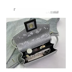 Vue macro montrant les compartiments internes et le motif serpent de ce sac bandoulière chic