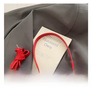 Detail of red lychee textured shoulder strap with metallic buckle on gray fabric