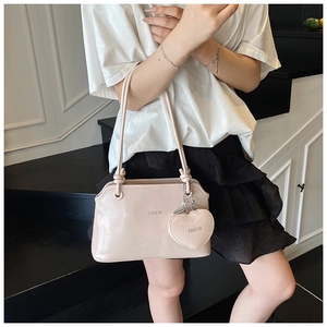 Gros plan du sac seau en cuir rose minimaliste avec breloque cœur et lettrage de marque