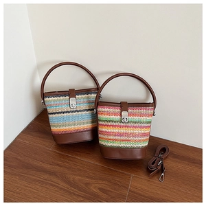 Detail of colorful rainbow woven straw bucket bag with leather base and round handle
