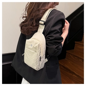 Detail of cream nylon crossbody bag with adjustable strap and front zipper pocket