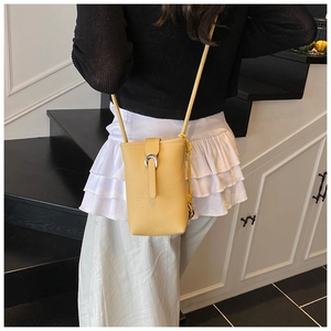 Détail d'un sac téléphone jaune à texture litchi avec boucle fer à cheval argentée