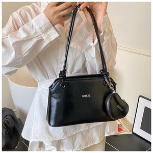Détail d'un sac seau en cuir noir brillant avec logo argenté et pochette cœur amovible