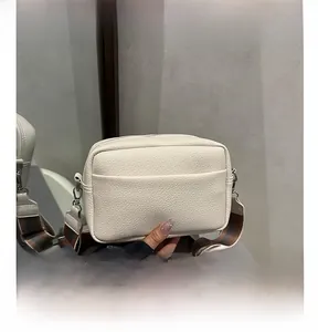 Close-up of cream textured leather crossbody camera bag with striped woven strap