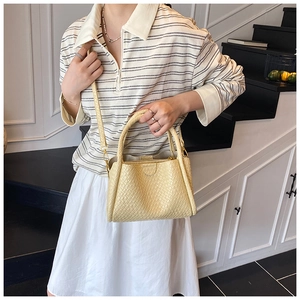 Détail du sac seau tressé beige clair montrant la texture et les ferrures dorées