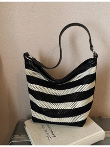 Classic black and white striped woven tote bag with leather straps on a modern background