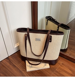 Macro detail of large woven tote bag with brown leather trim and metal logo plate