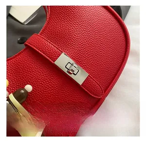 Detail of red lychee leather bag with silver twist lock and cartoon charm pendant