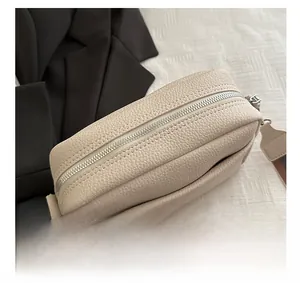 Close-up of litchi texture cream crossbody bag with silver zipper and wide strap