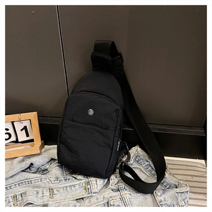 Close-up of black nylon crossbody bag with metal logo and adjustable wide shoulder strap