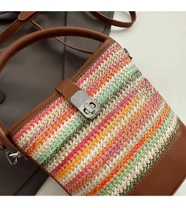 Detailed texture of rainbow woven straw bucket bag with dark brown leather trim and metal lock