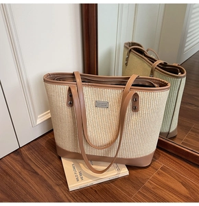 Macro detail of French straw tote featuring contrast brown leather trim and metal logo