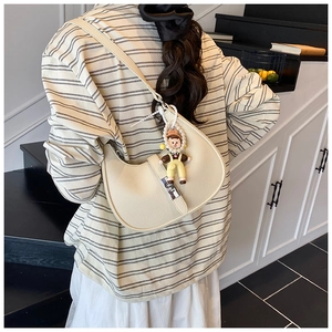 Detailed view of cream crescent hobo bag featuring litchi texture and pearl charm
