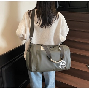 Sac de voyage vert olive porté en bandoulière, illustrant la taille et la grande capacité