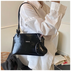 Détail du sac seau noir en cuir PU brillant avec porte-monnaie en cœur et ferrures argentées