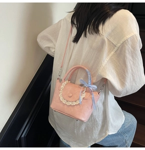 Pink bucket bag with lace trim and blue checkered bow detail on the handle