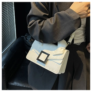 Detailed view of white snake pattern crossbody bag with black buckle and bow decor