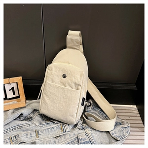 Detail shot of a cream nylon chest bag featuring a sturdy metal hook and wide strap