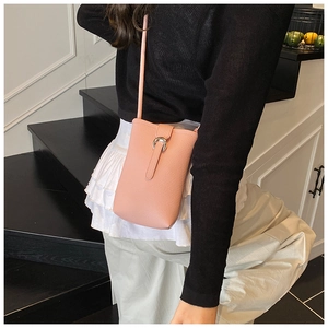 Detail of pink pebbled leather crossbody bucket bag with silver horseshoe buckle on model