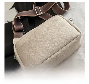 Detail of off-white lychee texture camera bag with adjustable striped fabric shoulder strap