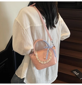 Detail of pink faux leather bucket bag with white lace trim and blue checkered ribbon bow