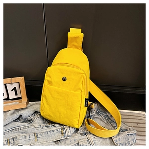 Detail of a bright yellow nylon chest bag featuring a zippered main pocket and wide strap