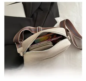 Internal capacity of beige crossbody bag with wide striped strap and zip closure