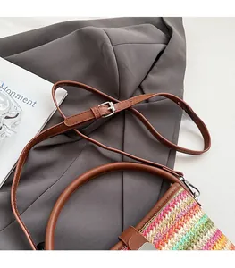 Detail of colorful rainbow woven bag featuring brown leather handle and adjustable strap