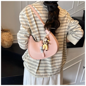 Close-up of pink pebbled leather hobo bag with a cute cartoon doll pendant on shoulder