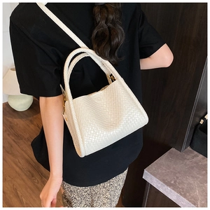 Gros plan de la texture tressée blanche et détails dorés sur le sac seau