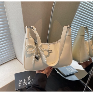 Detailed macro view of the cream PU leather handbag with pearl bow and silver heart pendant