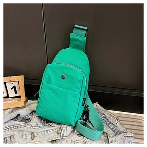 Detail view of water-resistant green nylon chest bag with metal logo and front zipper