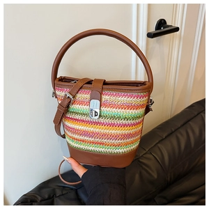 Detail of colorful woven straw bucket bag with brown leather trim and silver metal twist lock