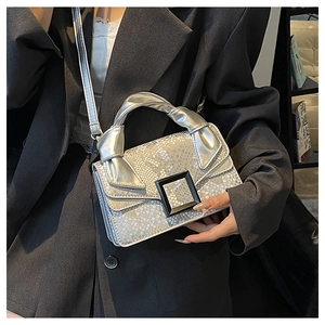 Silver snakeskin bag detail featuring a black square buckle and twisted top handle