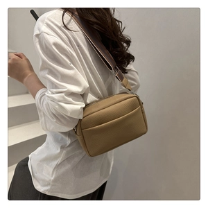 Close-up of khaki litchi grain PU leather crossbody bag with a wide striped fabric strap